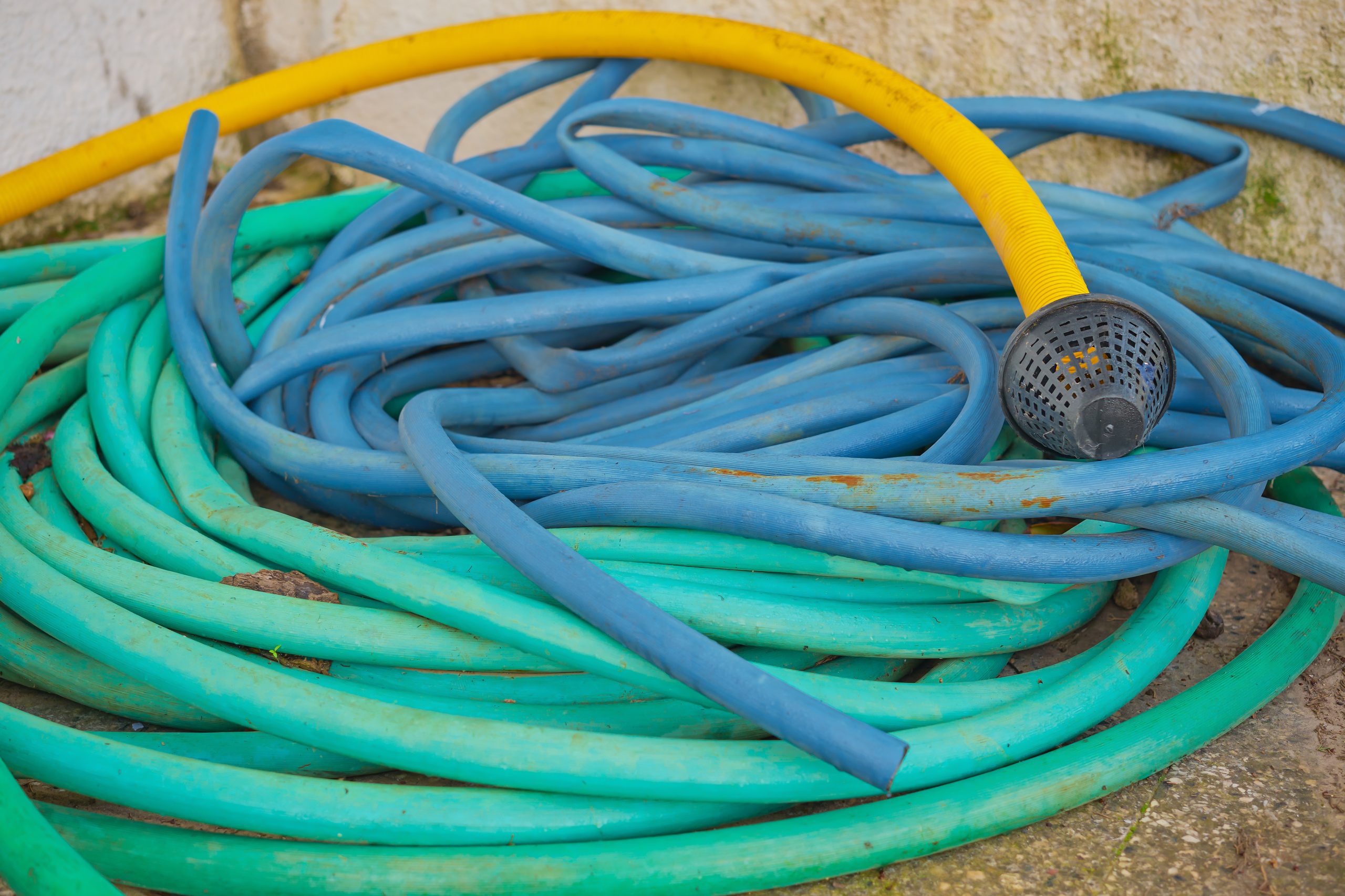 Hoses pile of multi colored hoses for watering the garden and for water supply, selective focus, plumbing and water dispenser equipment, reuse of materials