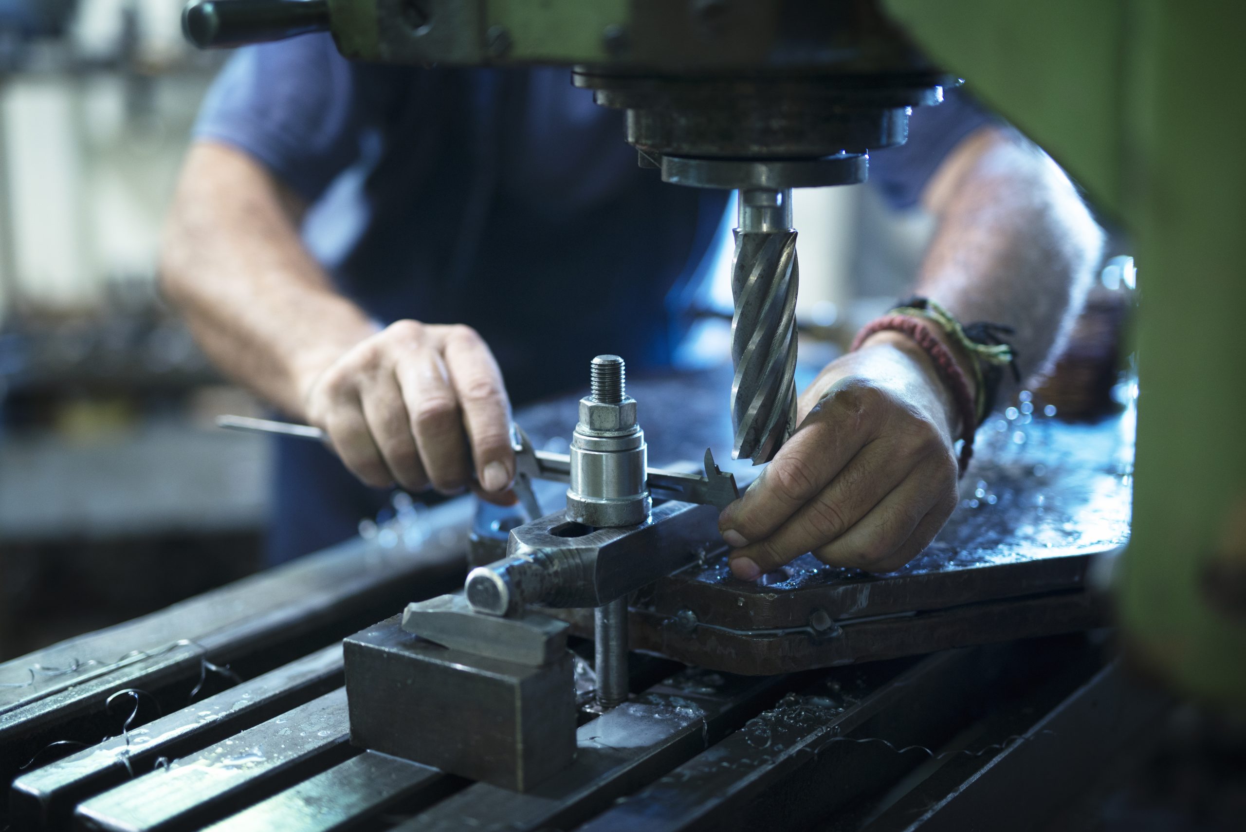 Machine Tools worker operating industrial machine in metal workshop.